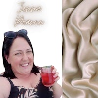 a woman is holding a glass of wine next to a piece of fabric